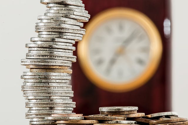 Coins on table with clock in background